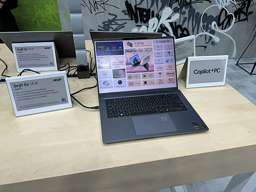 Un portatile aperto su un tavolo di legno chiaro, con schermi informativi e sfondo con graffiti bianchi e neri.