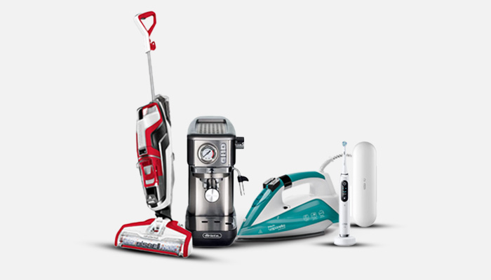 Su sfondo bianco, aspirapolvere rosso, macchina caffè acciaio, ferro da stiro turchese, spazzolino elettrico bianco.