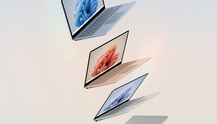 Tre computer portatili aperti sono disposti in verticale su sfondo chiaro. Ogni schermo mostra un'immagine diversa.