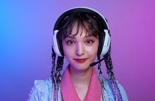 Primo piano di una persona con cuffie bianche, microfono e trecce colorate su sfondo blu e rosa.
