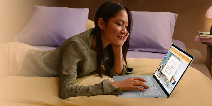 donna distesa sul letto sorride davanti ad un portatile asus acceso