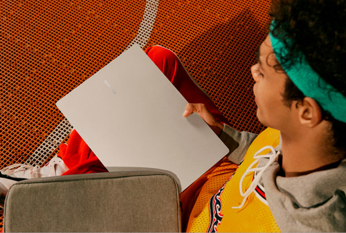 Ragazzo con fascia verde legge su campo da basket arancione. Ha una maglia gialla con bordi scuri.