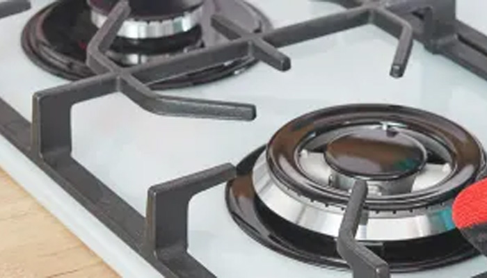 Primo piano di due fornelli a gas neri su un piano cottura bianco con un supporto per pentole nero.