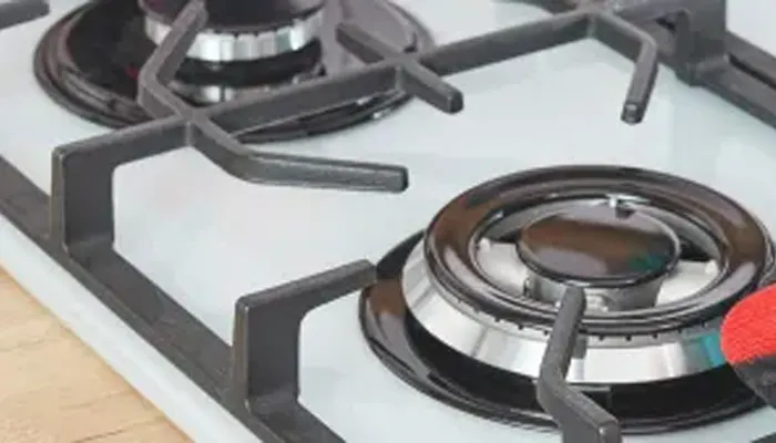 Primo piano di due fornelli a gas neri su un piano cottura bianco con un supporto per pentole nero.