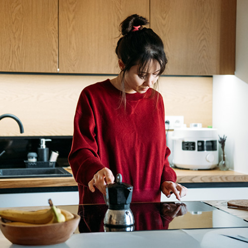 una donna cucina su un piano cottura a induzione nero