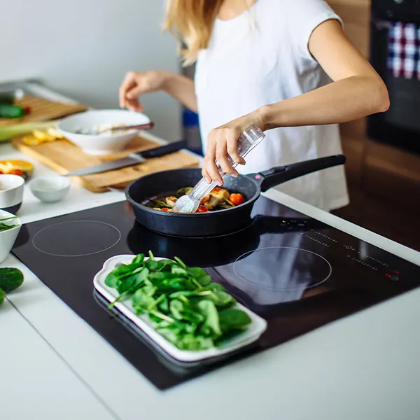 una donna cucina su un piano cottura a induzione nero