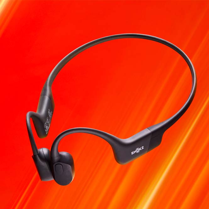 Cuffie nere Shokz su sfondo arancione. Le cuffie hanno un design avvolgente.