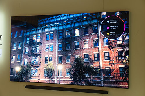 Schermo TV che mostra un edificio di mattoni con scale antincendio e un overlay circolare con dati.