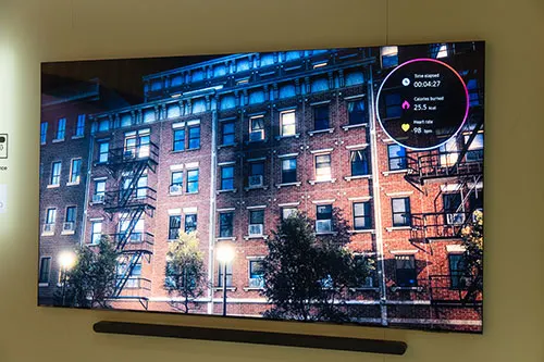 Schermo TV che mostra un edificio di mattoni con scale antincendio e un overlay circolare con dati.