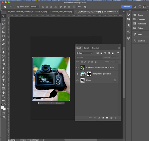 Schermata di Adobe Photoshop con una fotocamera digitale tenuta in mano, pannelli livelli aperti e strumenti a sinistra.
