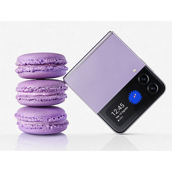 Tre macaron viola impilati accanto a un telefono pieghevole viola e nero su sfondo bianco.