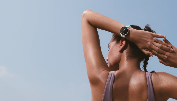 schiena di una donna che si allena e sta cone le braccia sulla testa e ha al polso un orlogio xiaomi