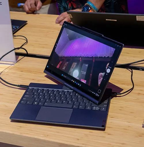 Un tablet nero su una tastiera nera su un tavolo di legno, con un display acceso che mostra immagini viola.