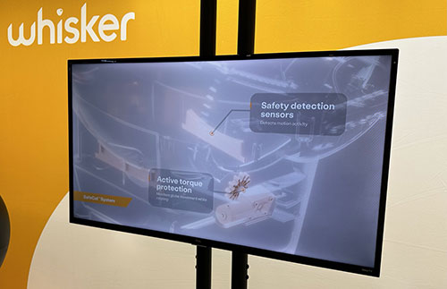 Monitor nero su supporto mostra sensori di sicurezza e protezione attiva su sfondo giallo e crema.