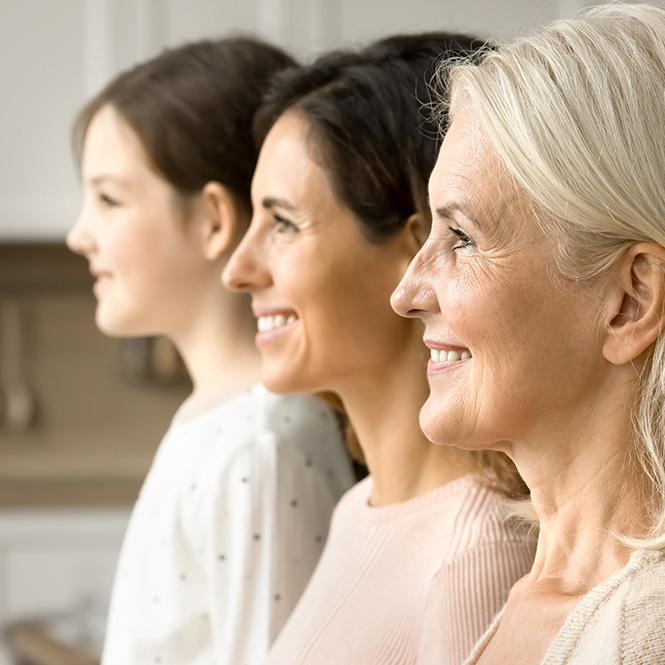 Tre donne di et� diverse sorridono di profilo. Indossano abiti chiari. Lo sfondo � sfocato e luminoso.