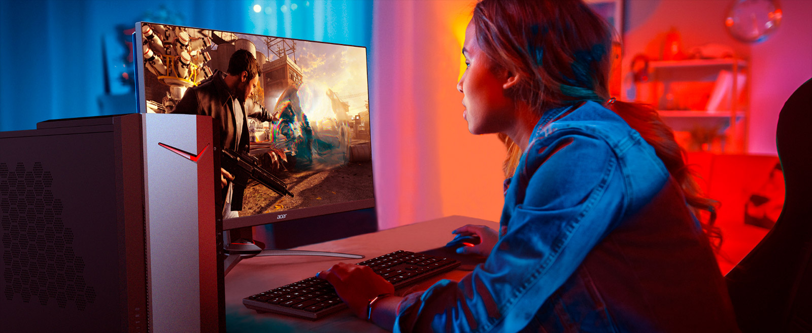 Ragazza che usa una tastiera davanti a un monitor che mostra un videogioco, con un PC desktop a sinistra.