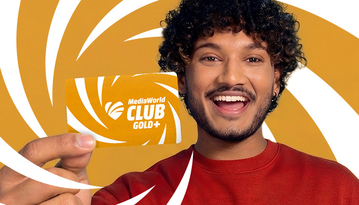 Donna in maglia rossa che indica tessera dorata MediaWorld Club Gold+ con spirale bianca.