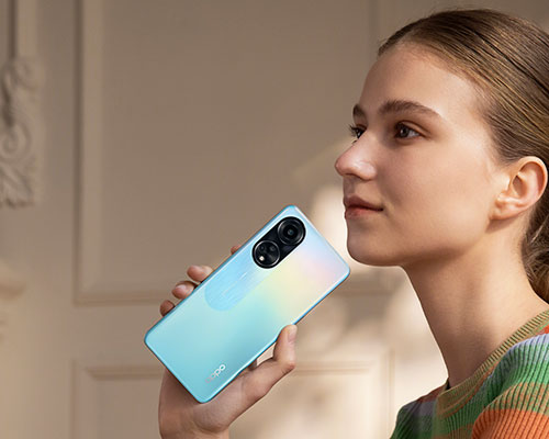 Donna tiene in mano un telefono azzurro con doppia fotocamera in un interno.