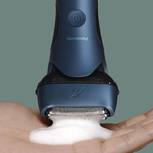 Rasoio blu su una mano con schiuma bianca. Sfondo grigio.