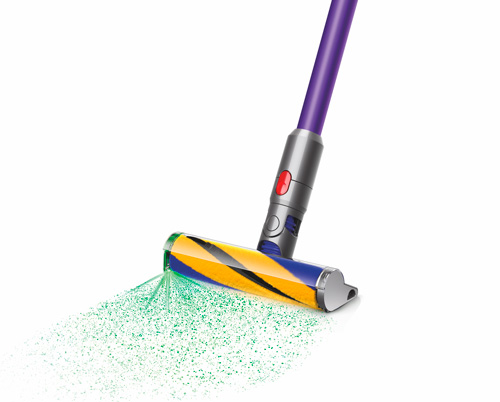 Aspirapolvere viola e grigio con spazzola a righe gialle e blu, che aspira polvere verde su sfondo bianco.