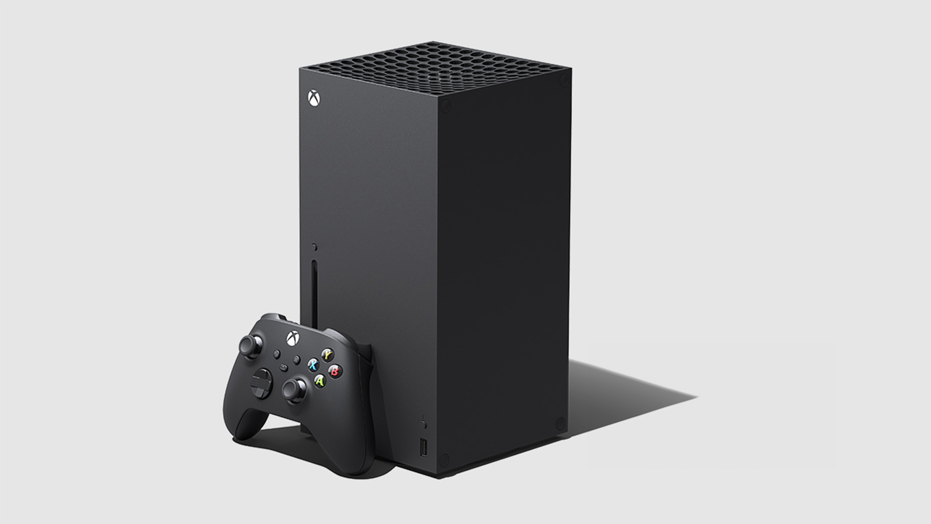 Ecco un'immagine di una console Xbox nera accanto a un controller su sfondo chiaro.