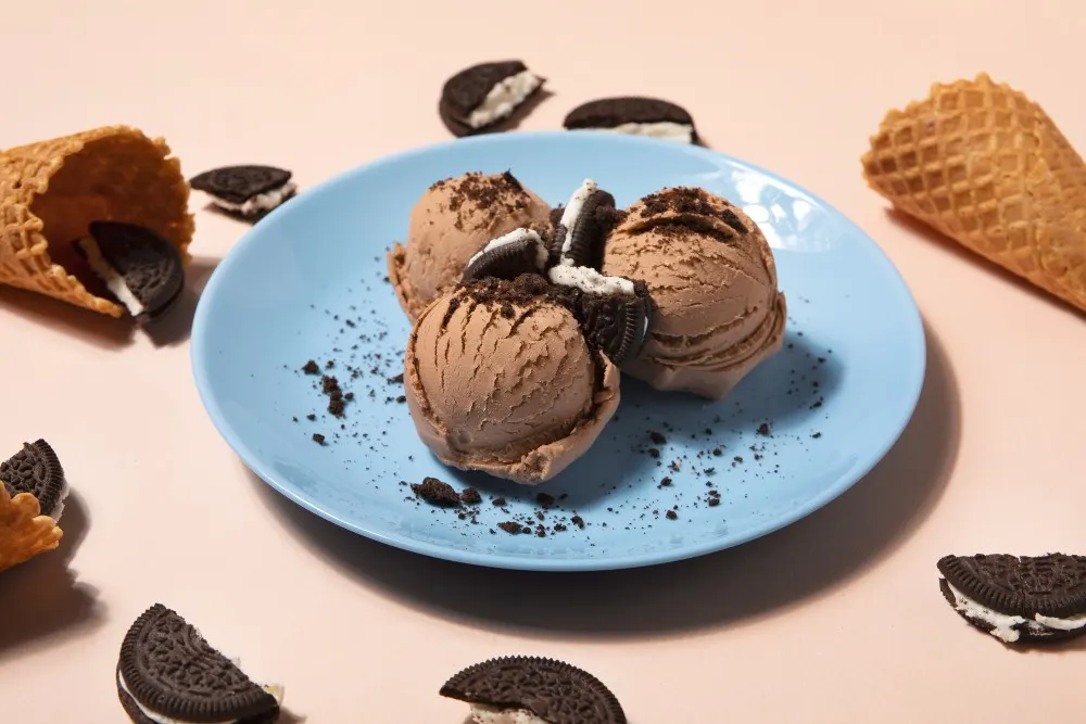 Palline di gelato cioccolato su un piatto e coni gelato.