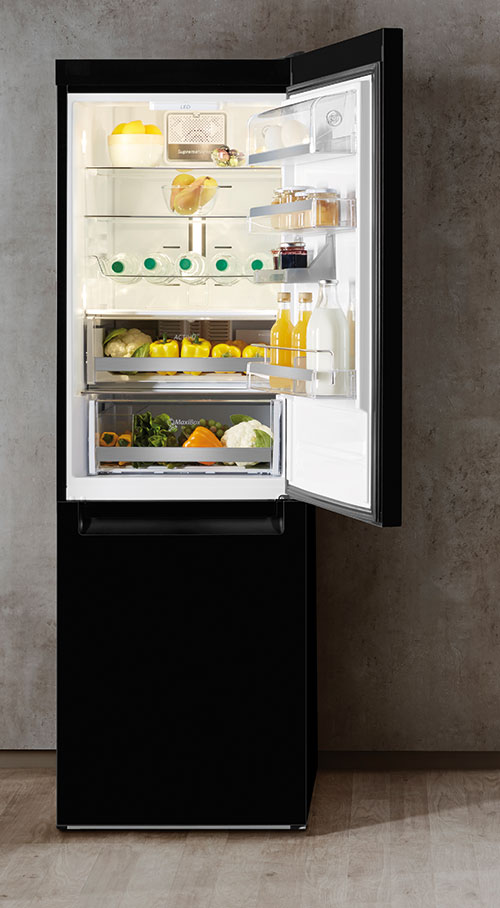 Frigorifero nero con porta aperta. Ripiani interni con cibi, bevande e verdure. Sfondo muro grigio.
