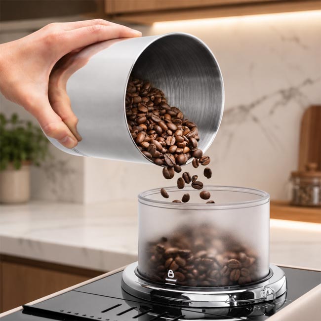 una mano versa dei chicchi in una macchina da caffè