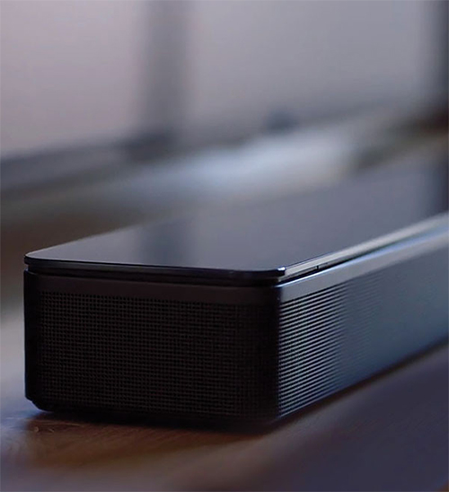 Una soundbar nera su una superficie chiara, con griglie e finiture che si distinguono in primo piano.