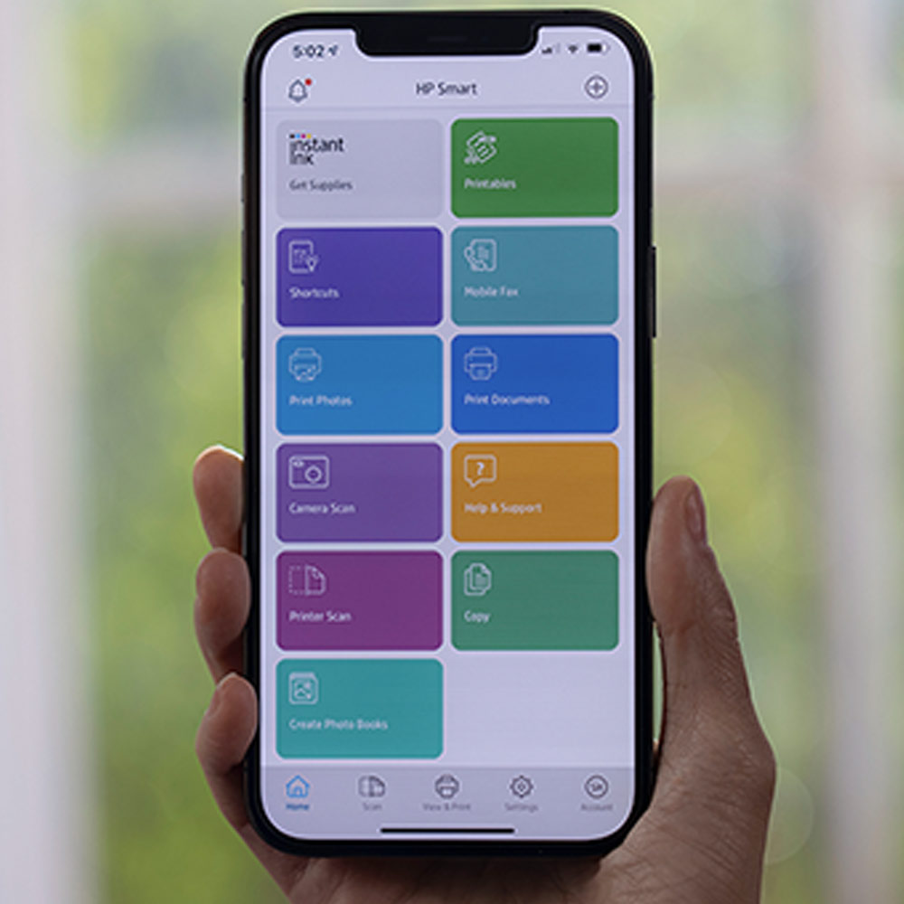 Smartphone con app HP Smart aperta, che mostra opzioni come "Printables", "Shortcuts" e "Camera Scan". Sullo sfondo, una finestra.