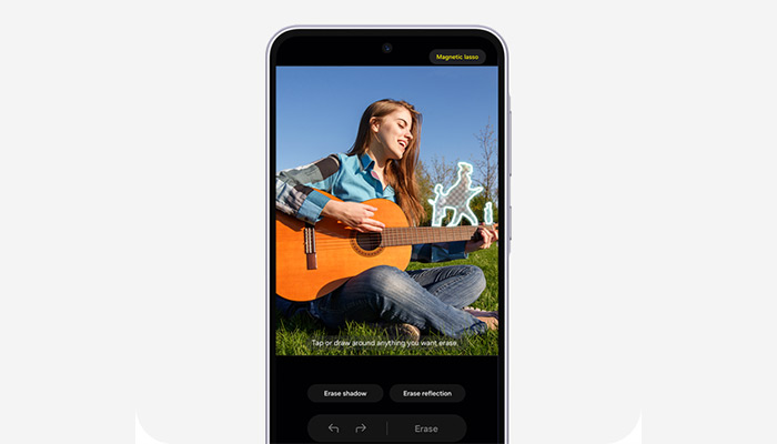 Donna che suona la chitarra sull'erba, visualizzata su uno smartphone. Sullo schermo, opzioni di modifica e cielo azzurro.