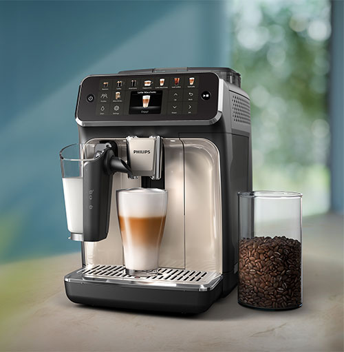 Macchina da caff� automatica con latte macchiato in preparazione. Un bicchiere di chicchi di caff� accanto.