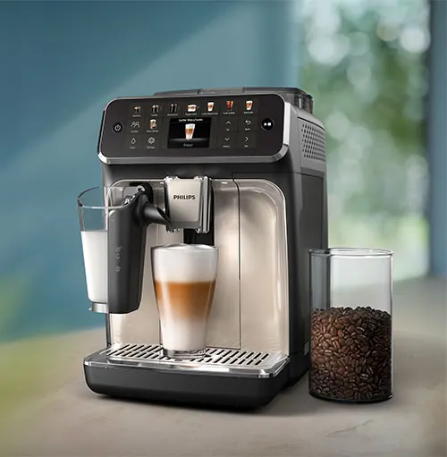 Macchina da caff� automatica con latte macchiato in preparazione. Un bicchiere di chicchi di caff� accanto.