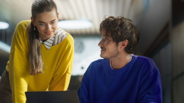 Una donna e un uomo sorridono davanti ad un notebook