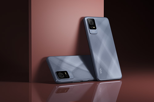 Due smartphone grigi, uno appoggiato a un blocco color terracotta, l'altro in verticale. Riflessi su superficie lucida.