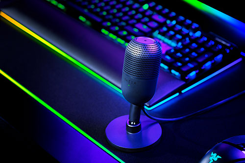 Microfono su scrivania con tastiera retroilluminata. Luce blu e verde.