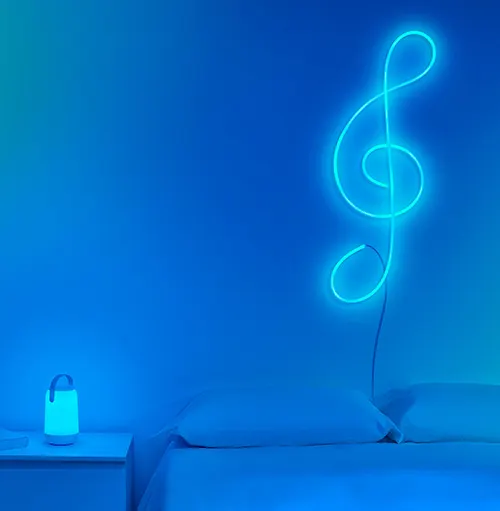 Lampada su comodino, chiave di violino al neon a parete sopra un letto. Tonalit� blu.