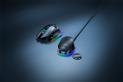 Mouse nero, base di ricarica con cavo e disco su sfondo blu. La base e il mouse hanno luci RGB colorate.