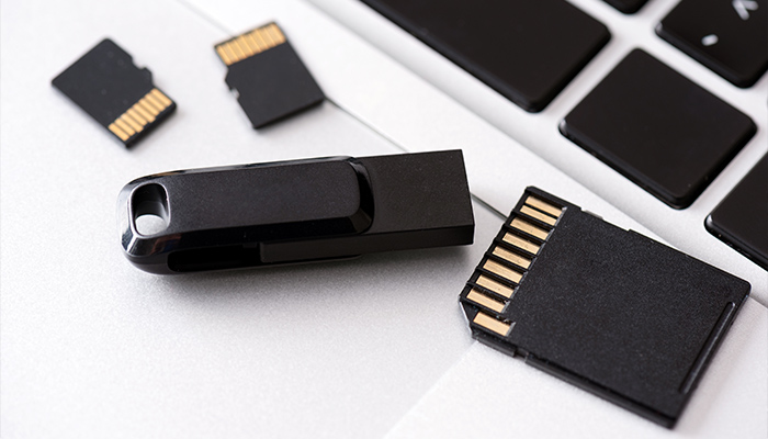 Su una tastiera bianca ci sono una chiavetta USB nera e alcune schede di memoria nere con strisce dorate.