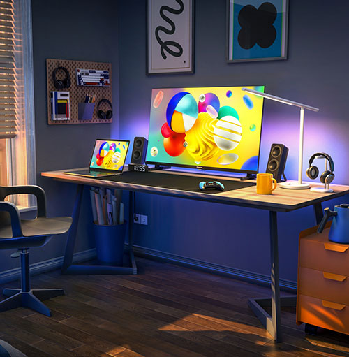 Scrivania con monitor, laptop, altoparlanti e cuffie. Sulla parete, decorazioni e una bacheca. Una finestra � parzialmente visibile.