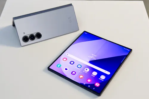 Su un tavolo bianco, un tablet aperto con icone colorate e un altro piegato con tre obiettivi della fotocamera.