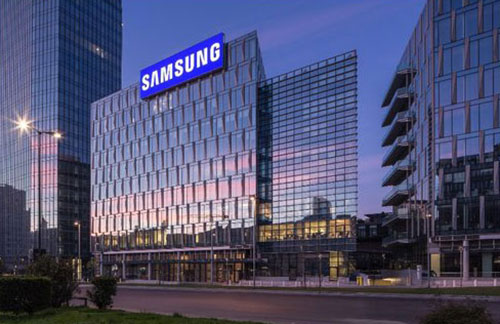 Edifici moderni con vetrate riflettono il cielo. Un edificio ha l'insegna "SAMSUNG" in blu.