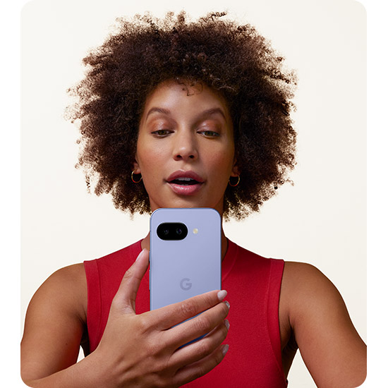 Donna con maglia rossa che tiene un telefono blu-lavanda con logo "G" su sfondo bianco.