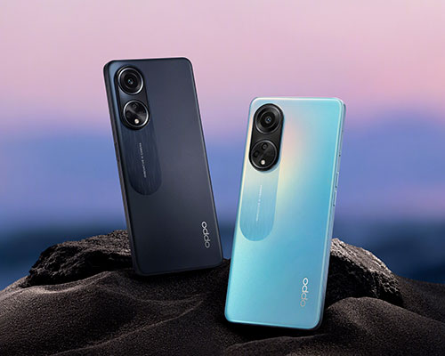 Due smartphone, uno blu scuro e uno azzurro, appoggiati su una superficie scura. Sullo sfondo, cielo con sfumature rosa e blu.