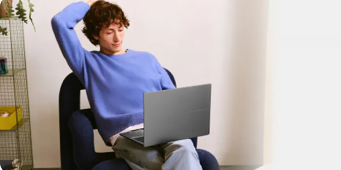 ragazzo seduto su una sedia tiene un portatile asus sulle gambe
