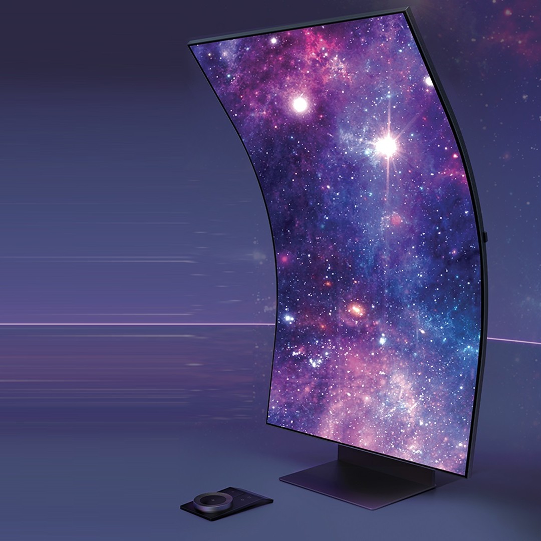 Schermo curvo con immagine di galassia su base quadrata; telecomando nero in basso a sinistra. Sfondo sfumato viola.