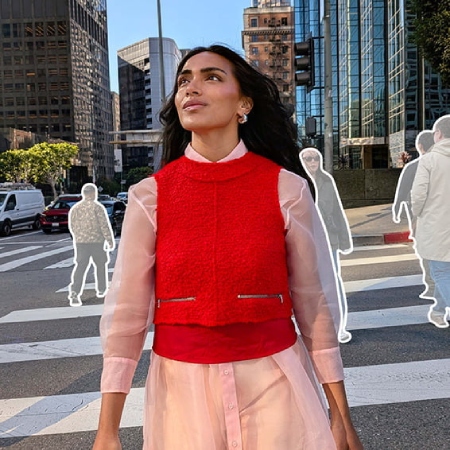 donna vestita di rosso e ripresa mentre sta camminando sulle strisce pedonali e guarda in alto