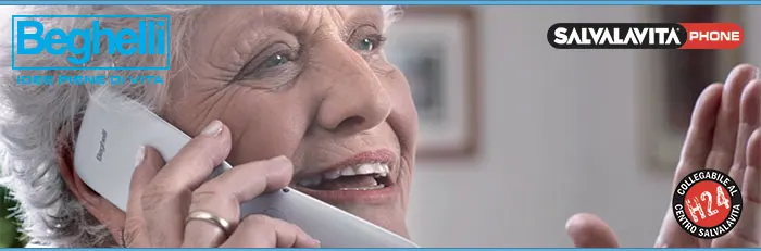 Pubblicità di Beghelli Salvavita Phone. Donna anziana usa telefono bianco. Logo prodotto in evidenza.
