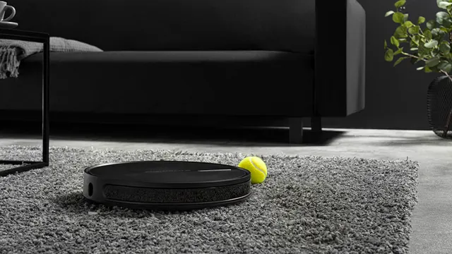 Zwarte robotstofzuiger en gele tennisbal op grijs tapijt. Zwarte tafel, bank en plant op de achtergrond.