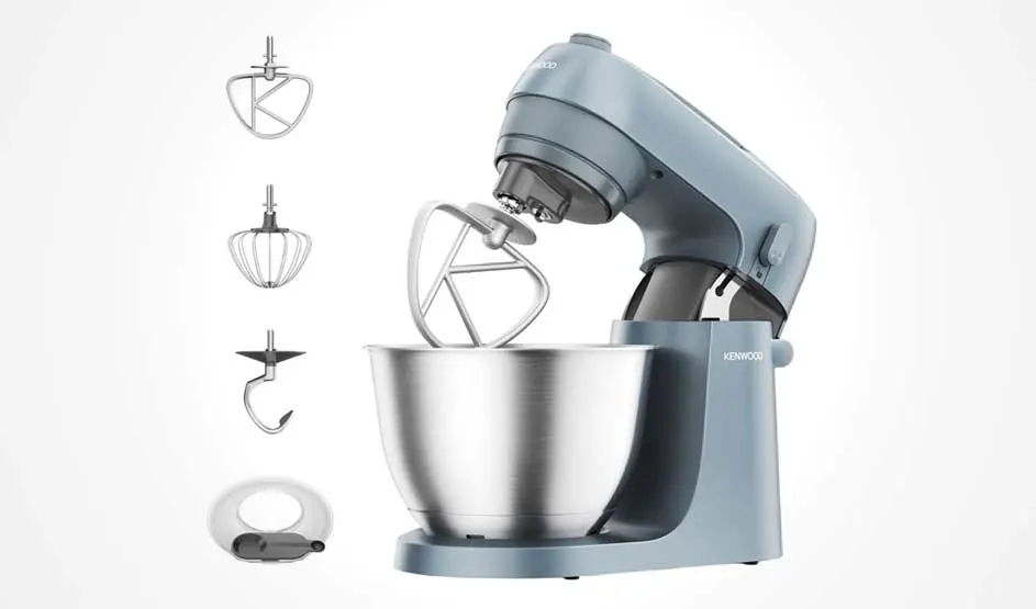 Een blauwe Kenwood keukenmachine met metalen kom staat op witte achtergrond; links staan pictogrammen van garde, klopper, haak en spatdeksel.